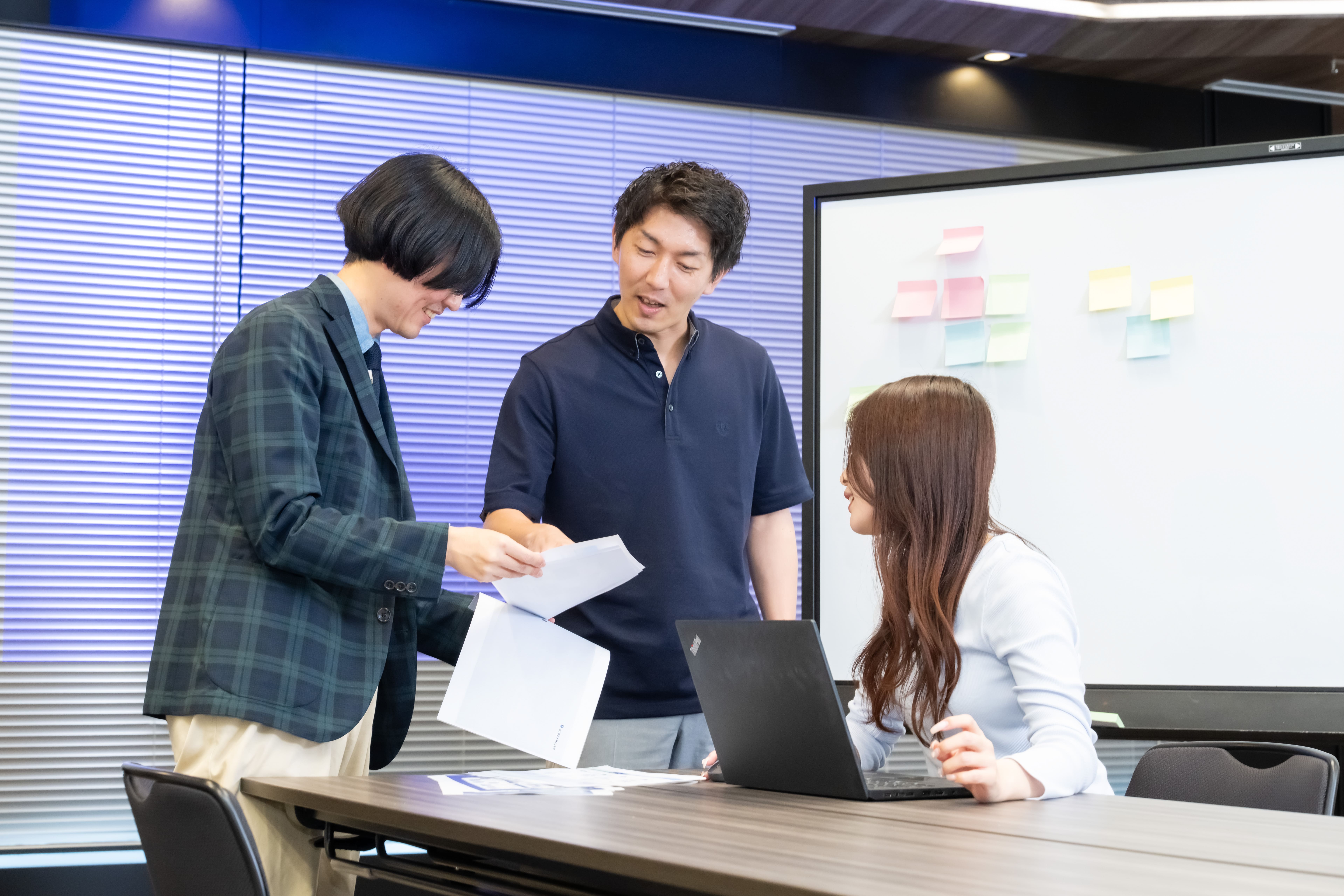 ホワイトボードの前で資料の構成や訴求ポイントを徹底的に検討するミーティング風景
